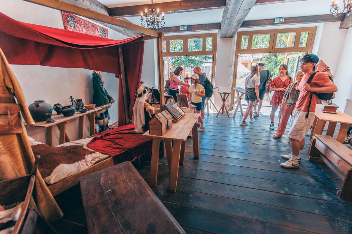 Une salle remplie d'objets médiévaux avec des visiteurs à l'intérieur.