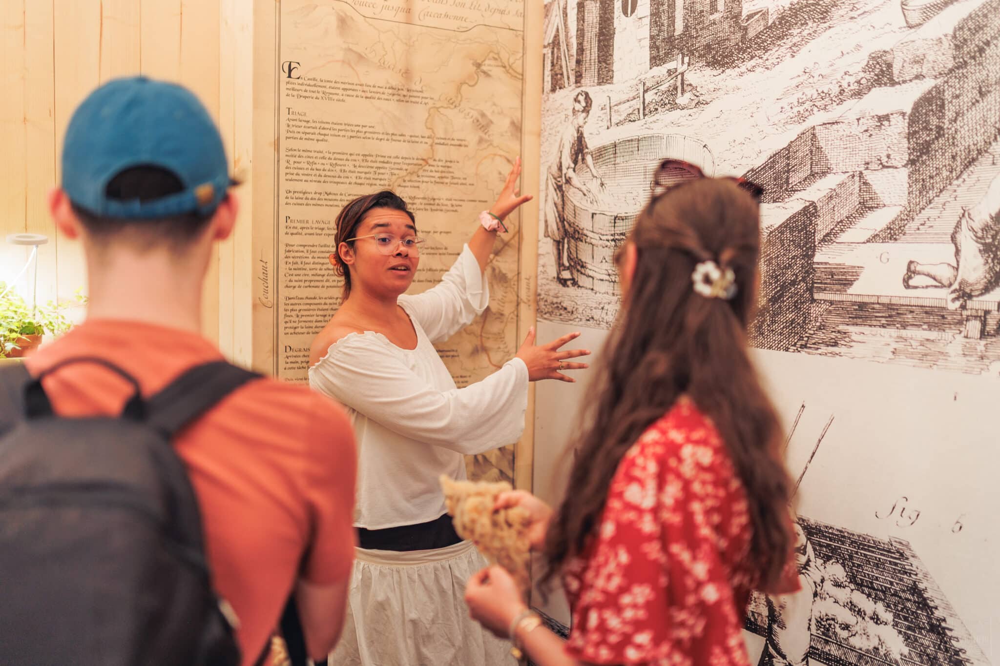 Serena animatrice saisonnière à la Maison de la Laine et du drap explique le lavage dans l'alcôve dédiée pendant sa visite.